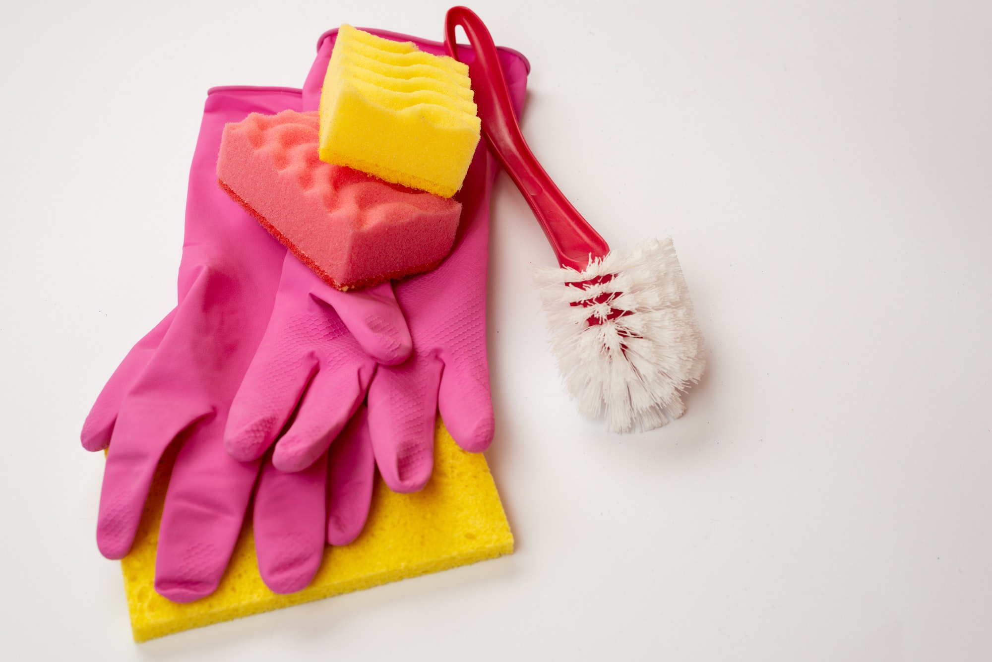 Sponge, household brush, latex gloves lying on a white background. Concept cleaning service